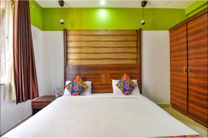 a bedroom with a white bed with a wooden headboard at FabHotel Ocean View Apartment, Dabolim in Old Goa