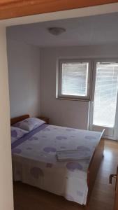 a bedroom with a bed and two windows at Apartments Dujlovic in Privlaka