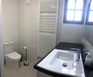 a white bathroom with a sink and a toilet at La petite Normande en ville in Louviers
