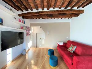 a living room with a red couch and a flat screen tv at CASA ILARIA - Luminoso appartamento con vista nel centro storico in Siena