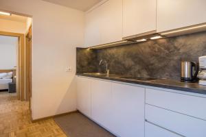 a kitchen with white cabinets and a sink at Rosalpina Apt 4 in San Vigilio Di Marebbe