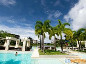 a person in a swimming pool with palm trees at Pico De Loro 2BR in Nasugbu