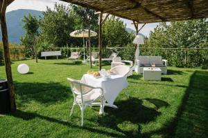 Agriturismo Tenuta Don Carlo في Nocera Superiore: طاولة وكراسي على العشب تحت البرغولية