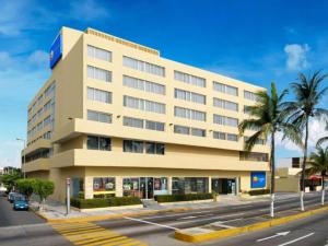 a large building on a city street with palm trees at Comfort Inn Veracruz in Veracruz