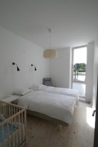 1 dormitorio blanco con 2 camas y ventana en Miško Apartamentai, en Juodkrantė