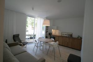 sala de estar con sofá, mesa y sillas en Miško Apartamentai, en Juodkrantė
