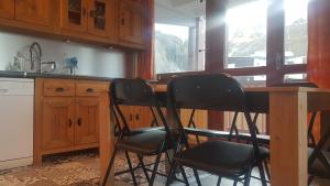 une cuisine avec trois chaises sur une table en bois dans l'établissement Plagne centre -Pied de pistes, à La Plagne Tarentaise