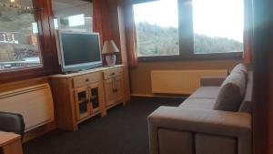 a living room with a tv and a couch and windows at Plagne centre -Pied de pistes in La Plagne Tarentaise