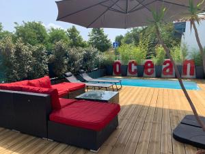 a patio with two couches and an umbrella next to a pool at Maison Guethary avec Piscine Privée in Guéthary