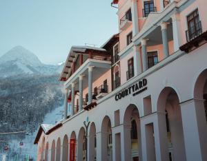 a large building with a view of the mountains at Courtyard by Marriott Sochi Krasnaya Polyana in Estosadok