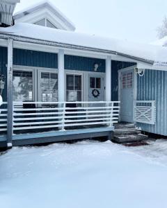 a blue house with a porch in the snow at Rukan Tähtihelmi Kelokivakka b12 in Ruka