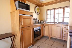eine Küche mit Holzschränken, einer Mikrowelle und einer Uhr in der Unterkunft Crimson Cottage in Dullstroom