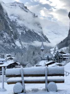 a bench covered in snow in front of a mountain at Chalet Pironnet with BEST Views, Charm and Comfort! in Lauterbrunnen