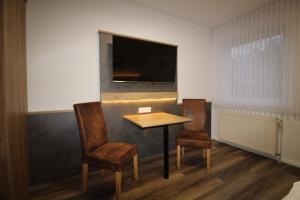 Zimmer mit einem Tisch, 2 Stühlen und einem TV in der Unterkunft Hotel Stubbe in Papenburg