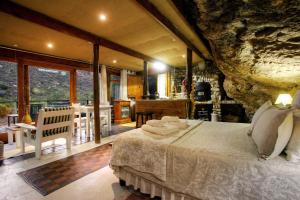 a bedroom with a large bed and a stone wall at Baviaanskloof Duiwekloof Lodge in Willowmore