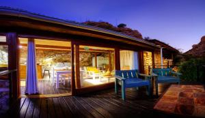 a house with a deck with chairs and a table at Baviaanskloof Duiwekloof Lodge in Willowmore