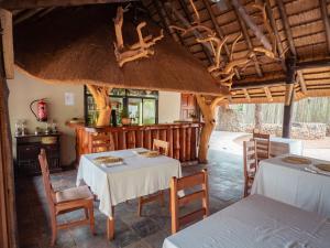 een eetkamer met 2 tafels en een keuken bij Rhino River Lodge in Manyoni Private Game Reserve