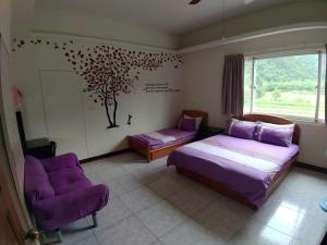 een slaapkamer met 2 bedden en een muurschildering van bomen aan de muur bij Lutenist B&B in Yuanshan