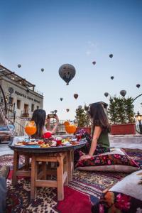 two girls sitting around a table with food on it at Agarta Cave Hotel in Goreme