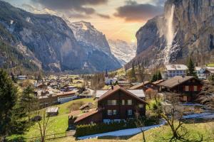 a village in the mountains with a waterfall in the background at Chalet Pironnet with BEST Views, Charm and Comfort! in Lauterbrunnen