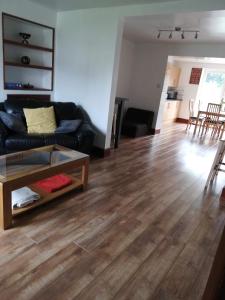 a living room with a black couch and a wooden floor at Comfy 3 bed house near Windsor Castle and Legoland in Windsor