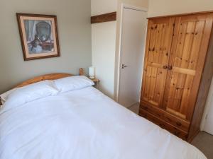 a bedroom with a white bed and a wooden door at Bayview Bungalow in Swansea