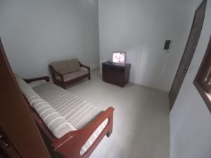 a room with a bed and a chair and a tv at Casa de praia Indaiá Bertioga in Bertioga