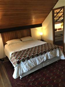 1 dormitorio con 1 cama grande y cabecero de madera en Casa Aldeia dos Pescadores - Agora com suíte e varanda no mezanino - PET Friendly, en Praia do Forte