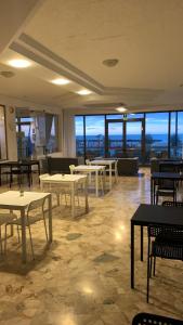 a dining room with tables and chairs and windows at Hotel Tritone Rimini in Rimini