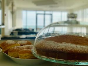 a plate of pastries and a cake in a glass dome at Hotel Tritone Rimini in Rimini