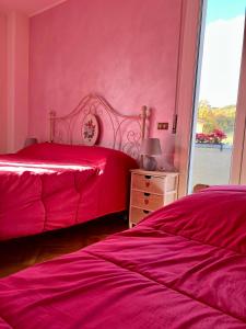 a bedroom with a red bedspread and a pink dresser at B&B del Lago in Sansepolcro