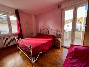 a bedroom with a red bed and two windows at B&B del Lago in Sansepolcro
