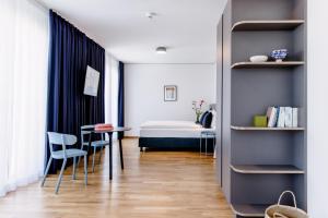 Cette chambre comprend un lit, une table et des chaises. dans l'établissement THE FLAG Meiller Gärten, à Munich