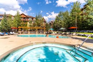 uma piscina num resort com cadeiras e árvores em The Raven Suite at Stoneridge Mountain Resort em Canmore
