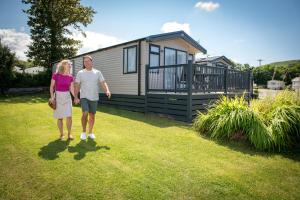 a man and woman standing in front of a tiny house at Llanrhidian Holiday Park in Llanmorlais