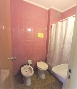 a pink bathroom with a toilet and a sink at Hotel América in Mar del Plata