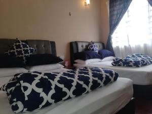 Cosy P6 Homestay في بوتشونغ: سريرين في غرفة مع وسائد زرقاء وبيضاء