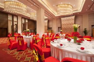 un salón de banquetes con mesas blancas y sillas rojas en Grand Mercure Beijing Central, en Beijing