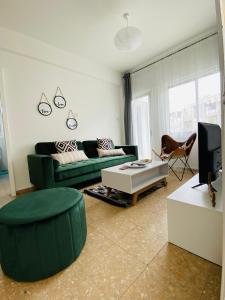 a living room with a green couch and a tv at Boho-Chic one bedroom flat in Engomi in Engomi
