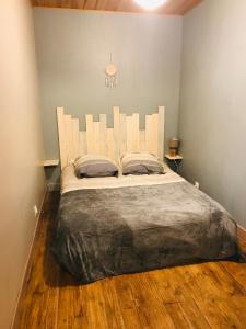 - une chambre avec un grand lit et une tête de lit blanche dans l'établissement P’tite House, à Bretenoux