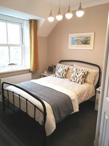 1 dormitorio con cama con almohadas y ventana en Ivy Bank Guest House, Tenby, en Tenby