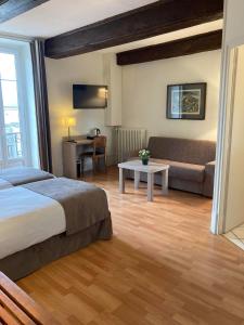 um quarto de hotel com uma cama e um sofá em Hôtel de la Poste em Pouilly-en-Auxois