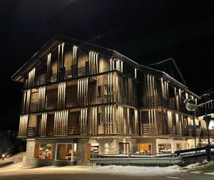 a wooden building with wooden shuttered windows at night at Hotel Silvana in Selva di Val Gardena