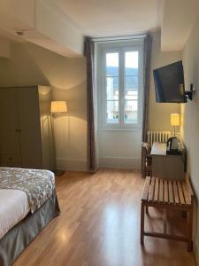 sypialnia z łóżkiem i dużym oknem w obiekcie Hôtel de la Poste w mieście Pouilly-en-Auxois