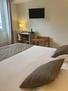 a bedroom with a bed and a desk with a television at Hôtel de la Poste in Pouilly-en-Auxois