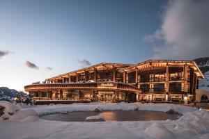 ein großes Gebäude mit einem Teich im Schnee in der Unterkunft Granbaita Dolomites in Wolkenstein in Gröden