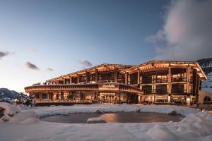 a large building with a pond in the snow at Granbaita Dolomites in Selva di Val Gardena