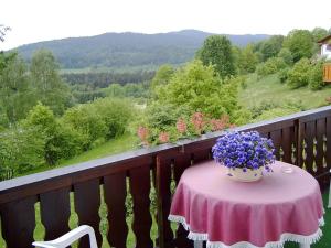 una mesa con un jarrón de flores púrpuras en el balcón en FW Zum Königshang en Bodenmais