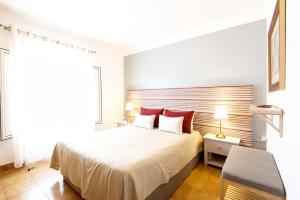 a bedroom with a large white bed with red pillows at Milfontes Private Homes - Duna Parque Group in Vila Nova de Milfontes