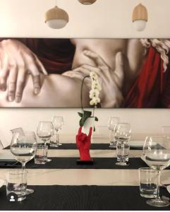 un tavolo con bicchieri da vino e un dipinto sul muro di Gonzaga Guest House a Napoli